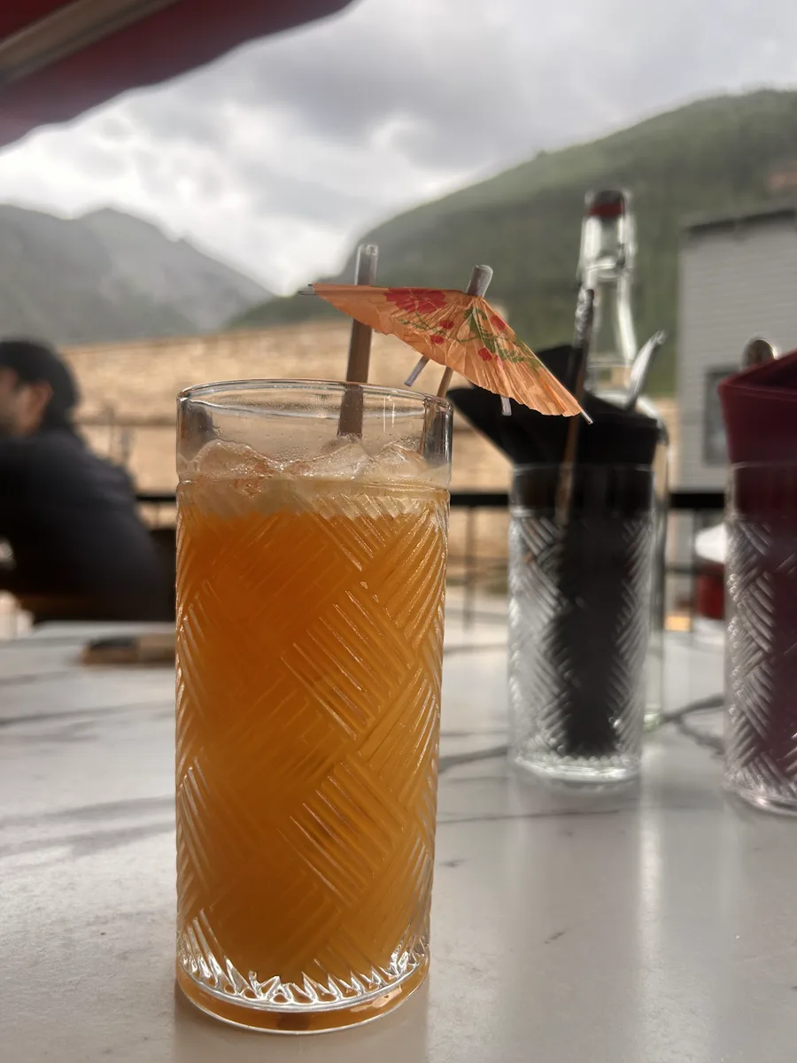 Tall amber drink at an outdoor table with mountains beyond
